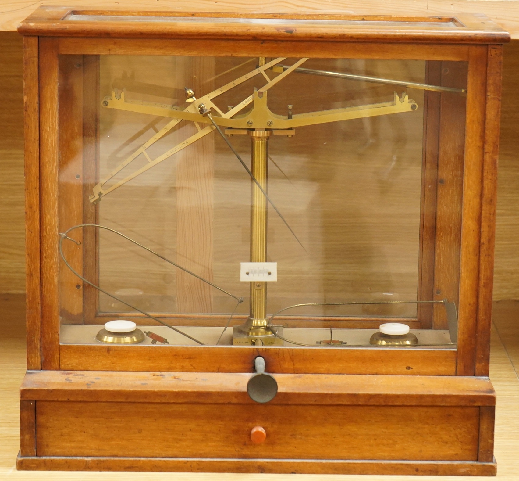 An early 20th century glazed mahogany cased laboratory chemical balance by Oertling, London, the drawer housing a set of weights, 45.5cm high, 50cm wide, 26cm deep